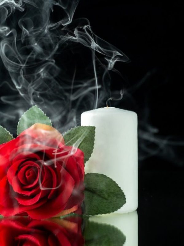 Front view of red rose with white candle on black